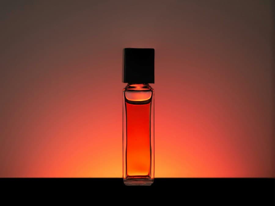 Amber perfume bottle photographed with dramatic warm backlighting