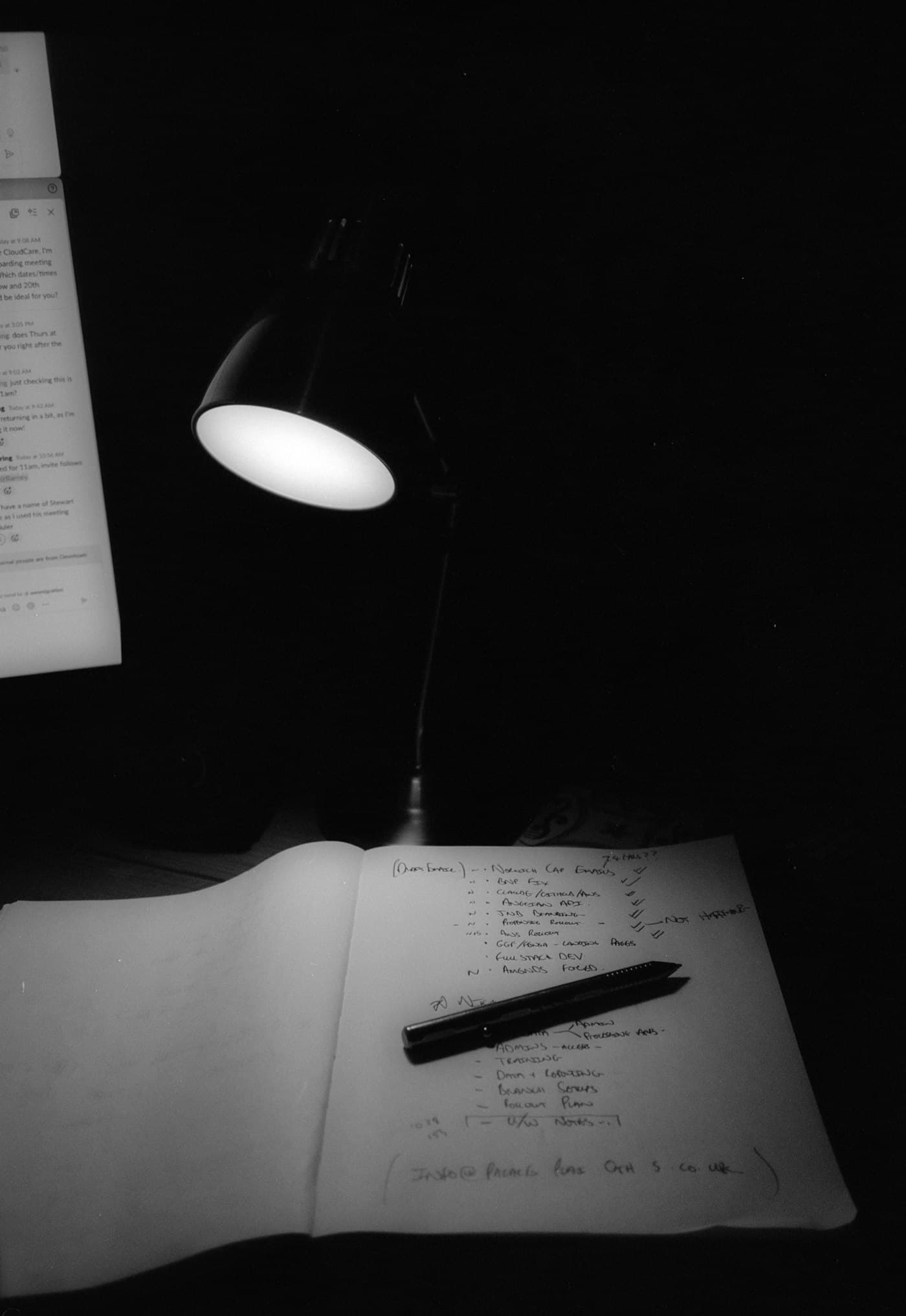 Desk lamp illuminating handwritten study notes and a pen